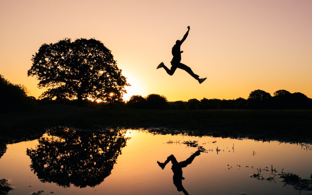 silhouette photo of man jumping on body of water during golden hour